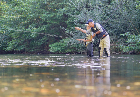 father-teaching-son-how-to-fly-fish-in-river father-teaching-son-how-to-fly-fish-in-river